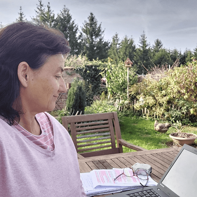 Marianne sitzt im Garten am Bloggen. Die Natur half mir meinen Meilenstein von 100 Blogartikeln zu erreichen