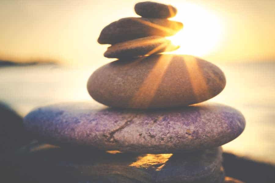 Aufeinander gestapelte Steine im Sonnenaufgang. Alles in Balance und ohne Stress.
