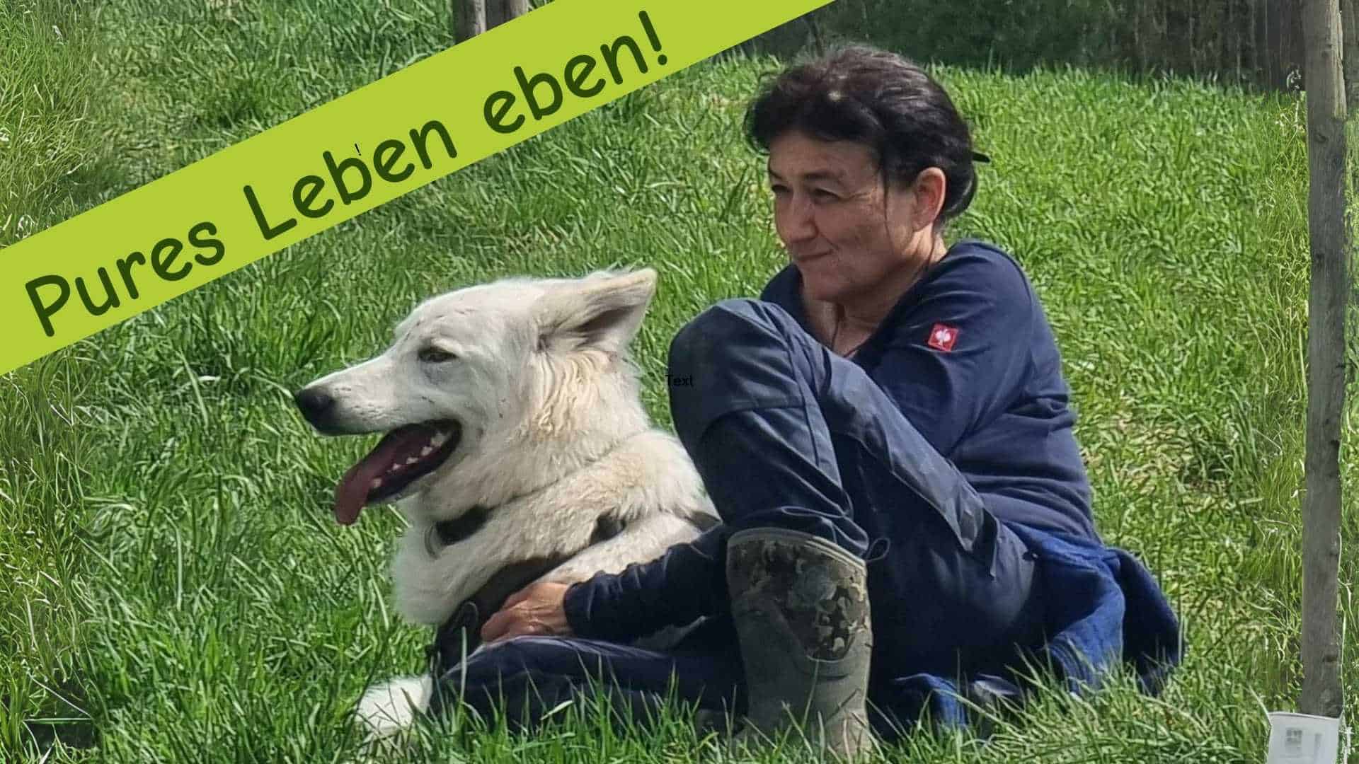 Marianne sitzt gemütlich am Boden mit ihrem Schäferhund-Rüden und taucht ein in die Natur. Darüber steht der Claim: Pures Leben eben!