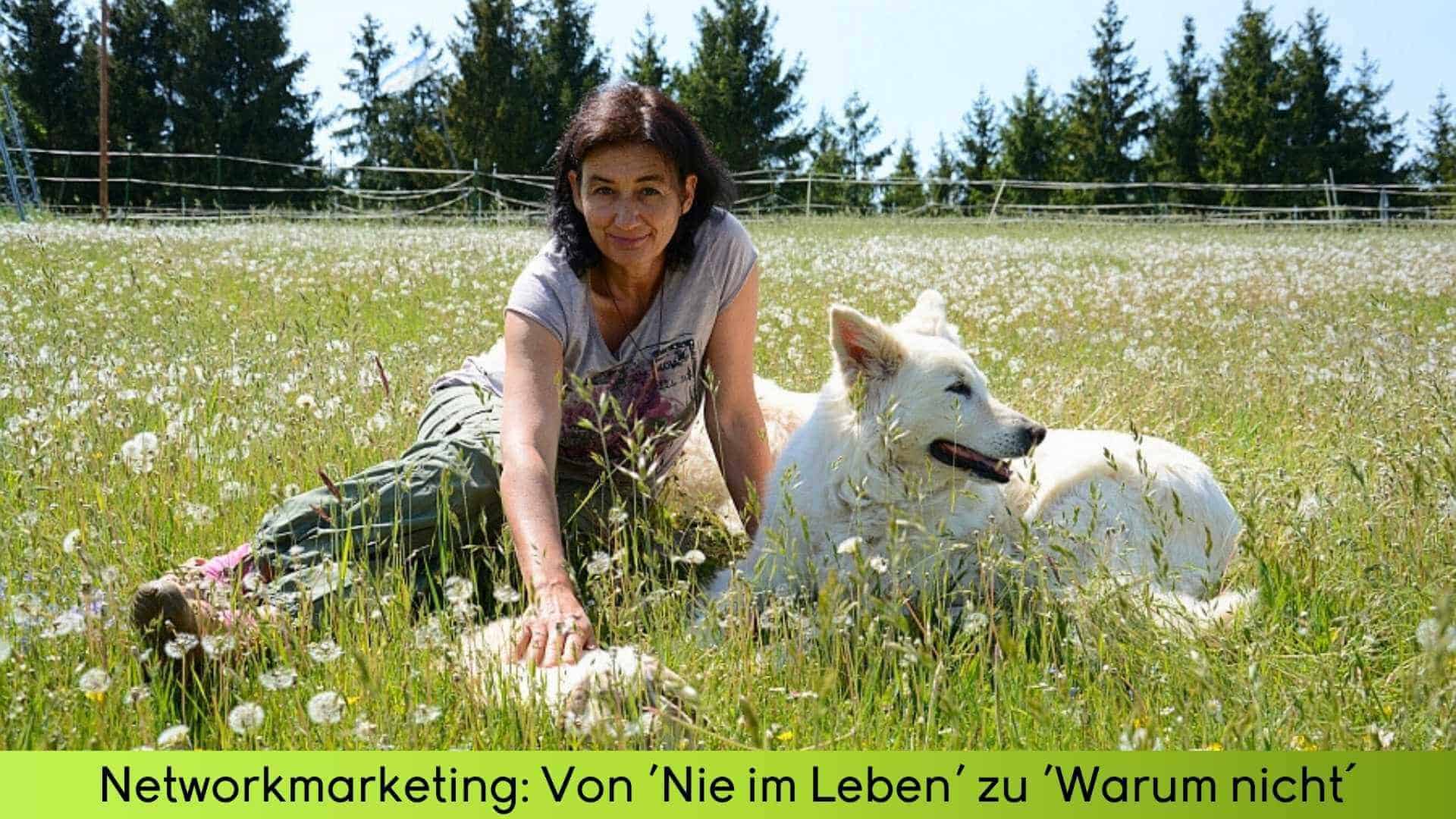 Marianne sitzt in einer Blumenwiese mit den Hunden und einem Kaninchen