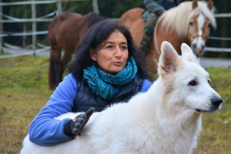 Marianne mit weißem Schäferhund am Boden, beide blicken in dieselbe Richtung.