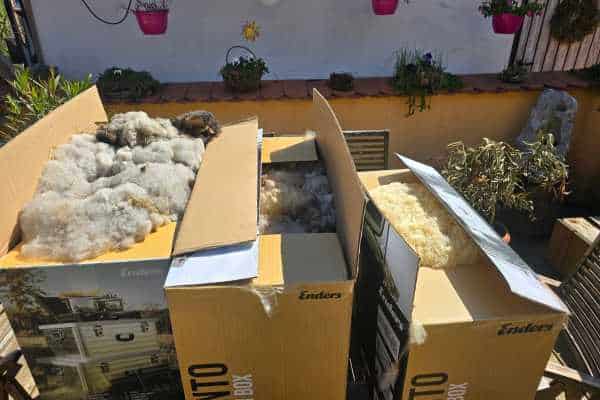3 Kartons mit Schafwolle stehen auf dem Gartentisch